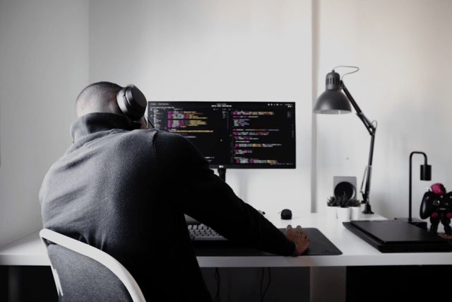 Man with headphones leaning over table.