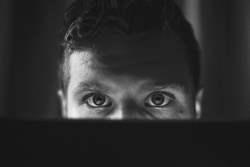 Man looking over laptop with shocking eyes.