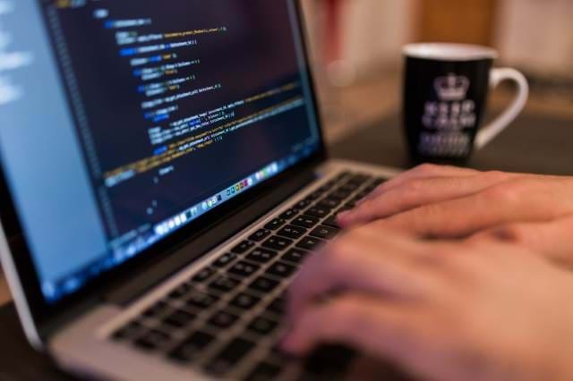 Man working on a laptop with a cup of coffee next to him