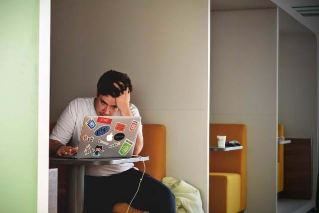 Man Sitting at a desk looking at a MacBook Pro