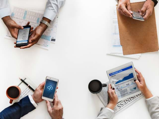 Group of people at a desk with smartphones and tablets