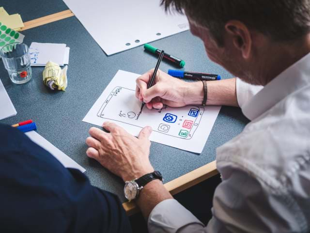 Man sketching out a design for a screen using a pen and paper