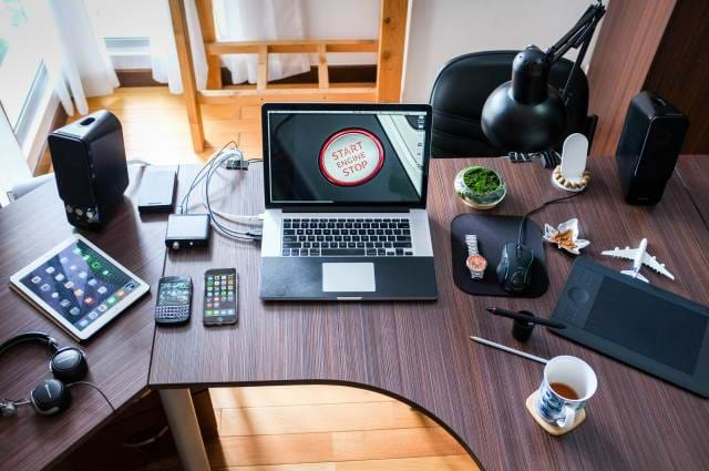 Desk with a number of gadgets around the computer