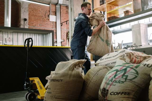 Man grabbing sacks of coffee beans.