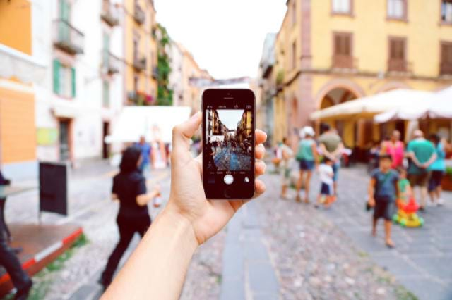 Man Holding Phone Taking A Picture Of Town