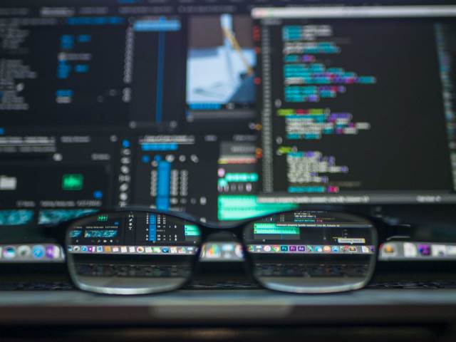 Glasses looking clearly at a fuzzy screen of code