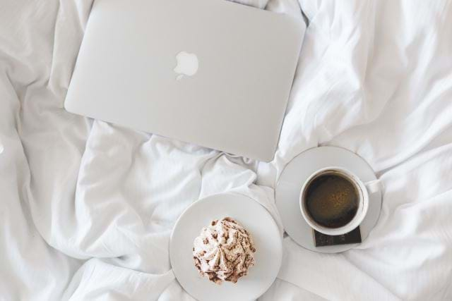 Apple computer, expresso, and breakfast on a bed