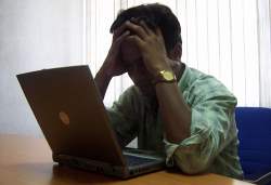 Man holding his head staring at a laptop