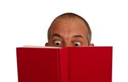 Man looking from behind a book with just eyes showing