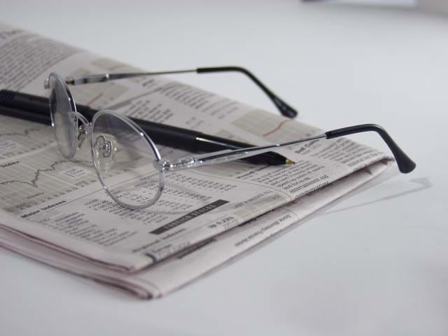 Picture of newspaper folder with a pen and glasses on it