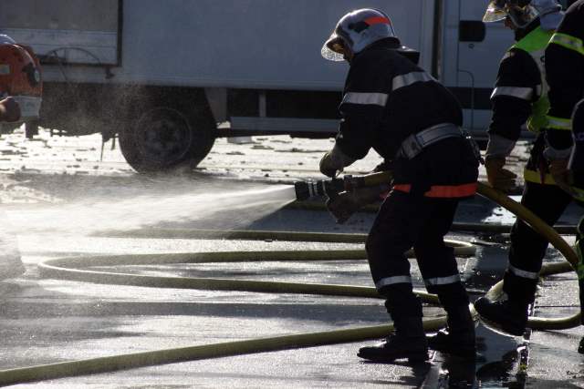 Fireman holding a firehose with water coming out.