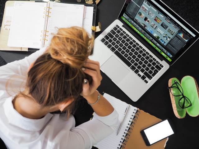 Woman holding her head in front of a laptop